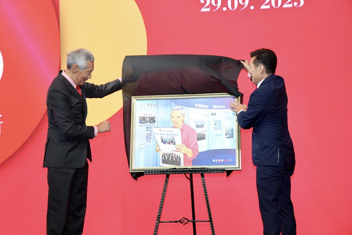 《联合早报》总编辑吴新迪为新总理李显龙献上由早报视觉部构思的特殊数码画作。作品中有李显龙出生日1952年2月10日的《南洋商报》和《星洲日报》封面;他手上拿着的则是2004年8月13日的《联合早报》,封面是他出任总理时组建的新内阁合照。(邝启聪摄)