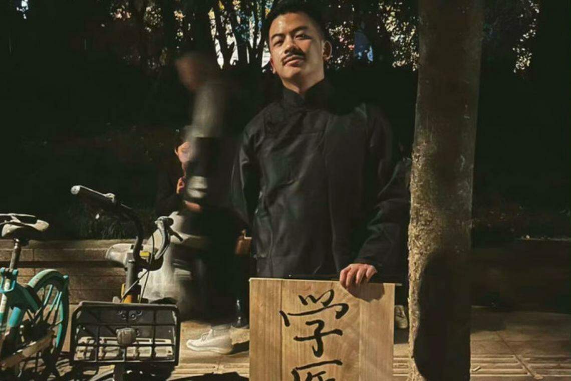 上海一名男子装扮成举着“学医救不了中国人”牌子的鲁迅。(互联网)
