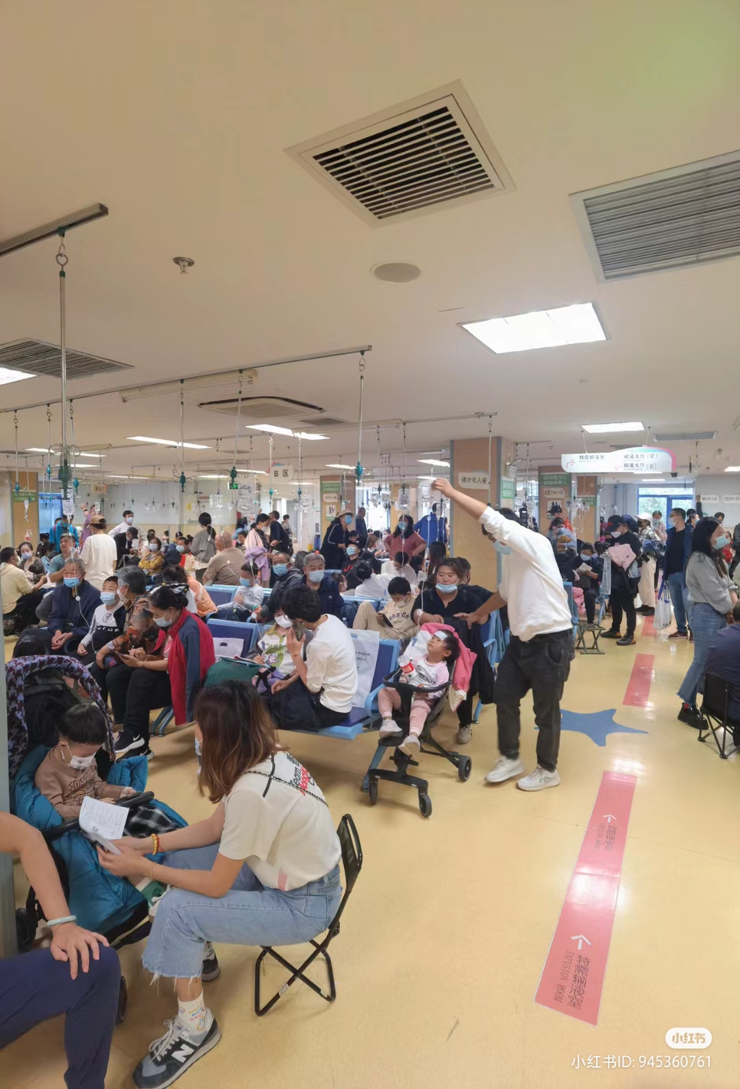 北京市儿童医院内挤满了家长和看病的孩子,其中有不少患儿坐在家长自备的折叠椅上,在医院走廊吊点滴。(互联网)