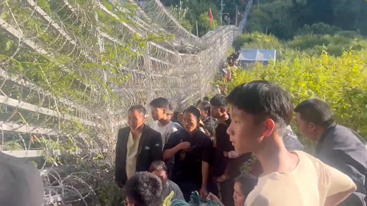 11月26日,缅甸掸邦老街县的民众为躲避战祸,逃到中缅边界的篱笆。(路透社)