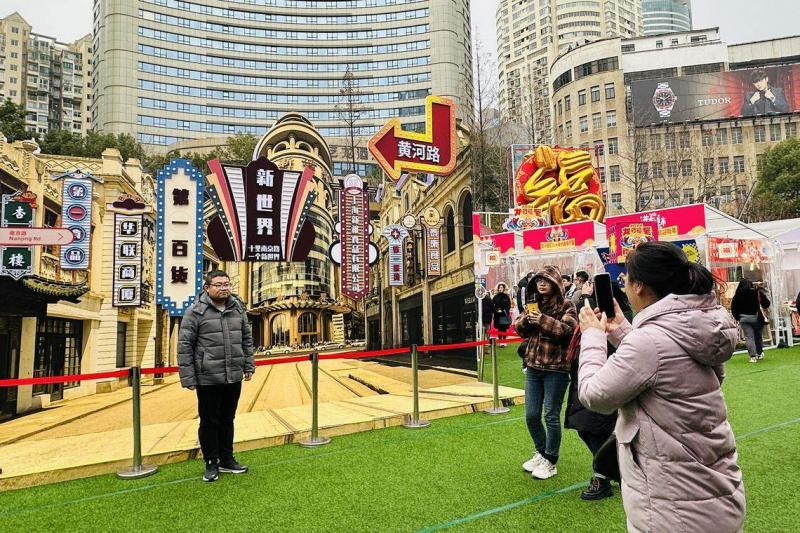 南京路步行街的龙年市集中央,是一整面仿照《繁花》年代南京路搭建的打卡墙,吸引不少游客上前合影。(陈婧摄)