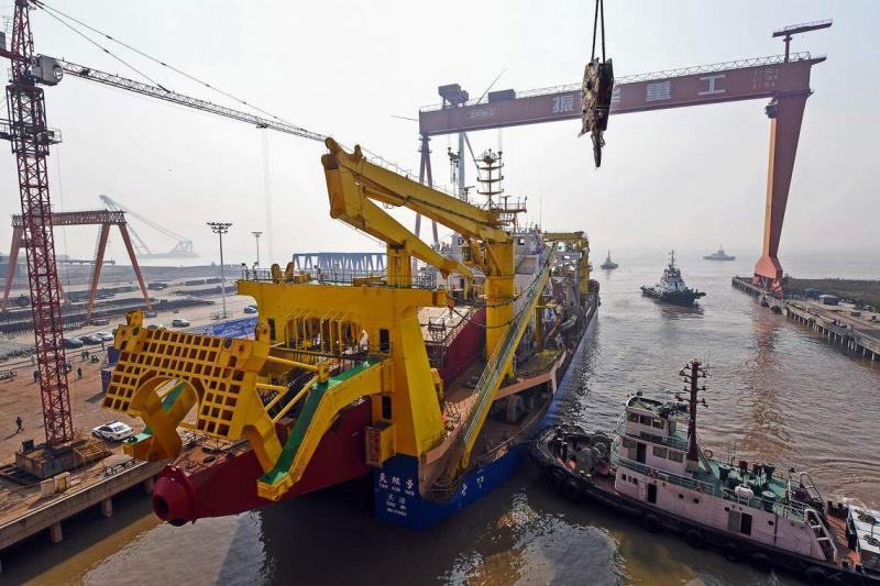 振华重工的业务领域包括港口机械、自动化码头、海洋重工、海上运输及安装、海上风电等。图为2017年11月3日位于江苏启东的上海振华重工造船厂,工作人员为自航绞吸挖泥船“天鲲号”下水进行最后的准备。 (新华社)