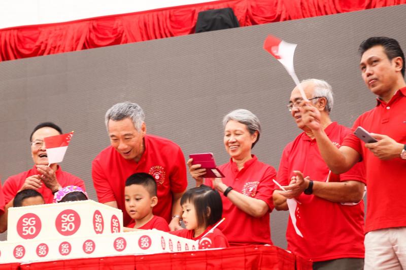 2015年8月9日,李显龙(左二)和夫人何晶(左三),在宏茂桥德义区的国庆敬礼仪式上,受邀上台切SG50金禧国庆蛋糕。(新明日报)