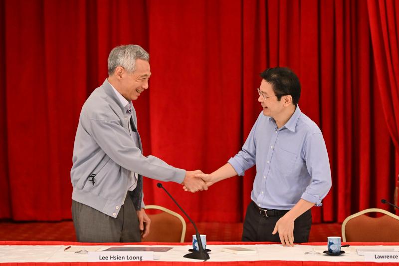 李显龙(左)于2022年4月16日在总统府举行记者会,阐述第四代领导人的遴选过程和各方面考量。图为李显龙与未来接班人、时任财政部长黄循财在记者会后握手。(海峡时报)