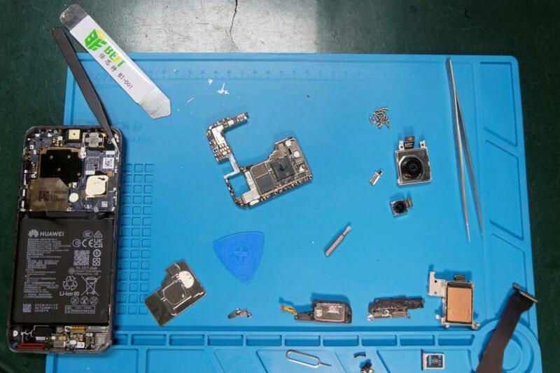在线技术维修公司iFixit的工作人员拆解华为Pura 70 Pro后,将其内部组件摆放在桌子上。(路透社)
