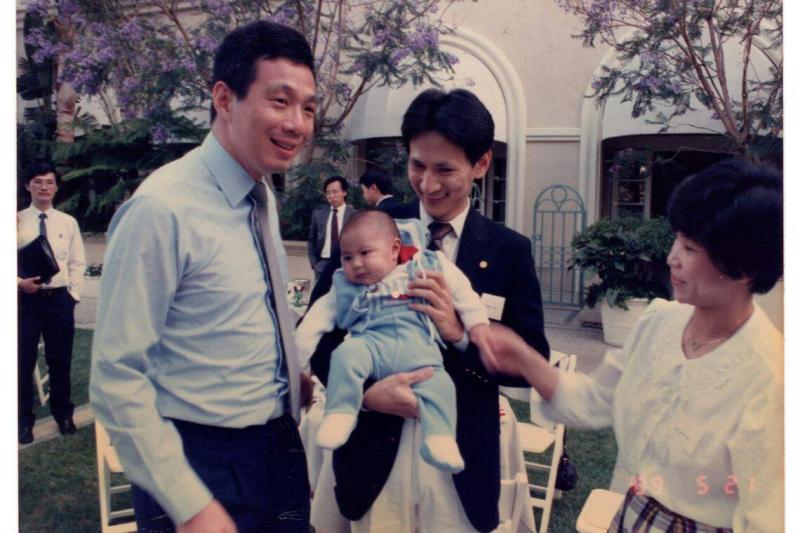 当年,时任贸工部长李显龙访美期间,在加州会见了旅居美国的新加坡留学生。洪振南(右二)当时抱着只有三个月大的儿子洪家豪(左二)与总理见面,照片也登上报纸。(受访者提供)
