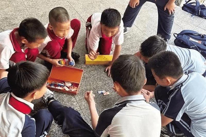 孩子们一般在放学时玩,他们三五成群趴在地上拍烟卡在近段时间成为校外常见的场景。(互联网)
