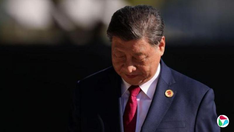 一张摄于2024年11月18日在巴西里约热内卢举行的G20峰会上的照片中,身穿深蓝色西装和红色领带,低头看向地面。